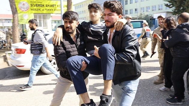 Ein verletzter Schüler wird von helfenden Händen weggebracht.