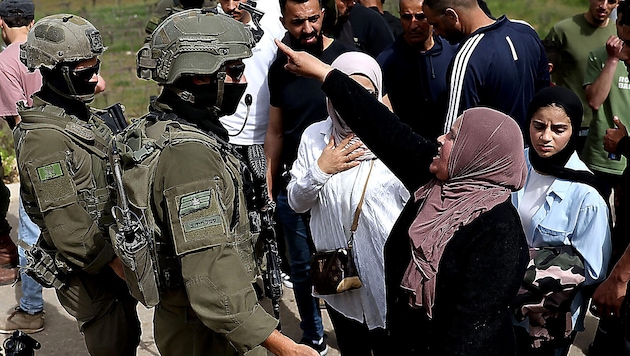 Palästinenser, die zu ihren Feldern im Westjordanland wollen, werden von israelischen Soldaten ...