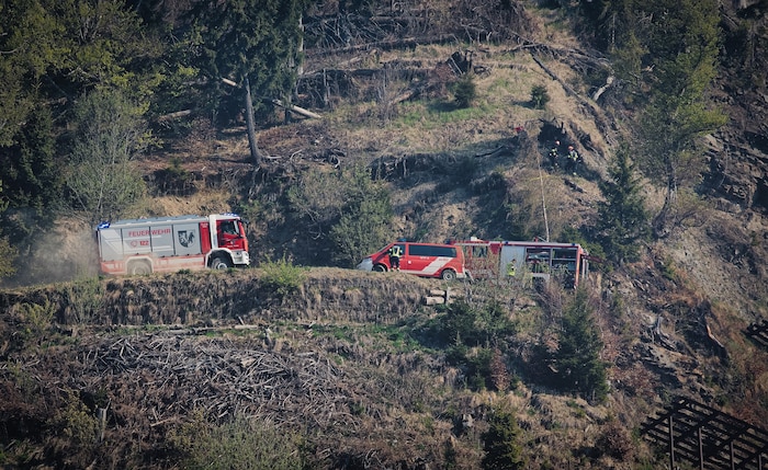 Feuerwehrmänner und Einsatzfahrzeuge im steilen Berggelände.