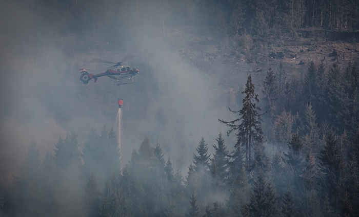 Ein Polizeihubschrauber wirft punktgenau Löschwasser ab.
