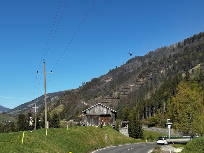 Der Hubschrauber fliegt mit dem Löschwasser ins Brandgebiet.