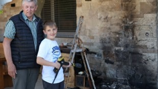 Opa Karl (68) mit Enkel Leo (11) und dem Hochdruckreiniger an der Brandstelle.