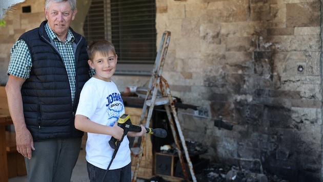 Opa Karl (68) mit Enkel Leo (11) und dem Hochdruckreiniger an der Brandstelle.