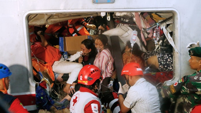 Helfer arbeiten daran, eingeklemmte Passagiere zu befreien.