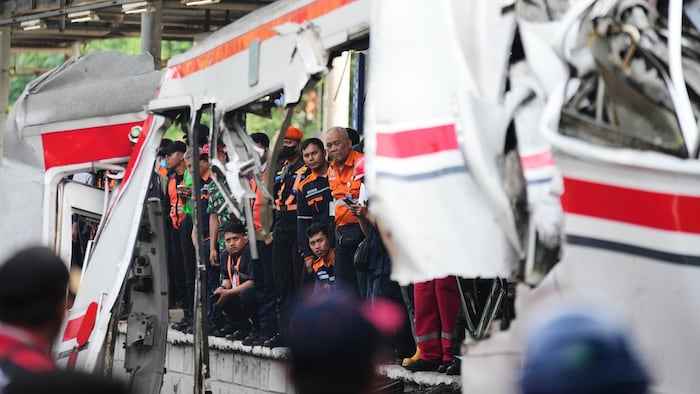 Arbeiter und Rettungskräfte begutachten das Wrack.