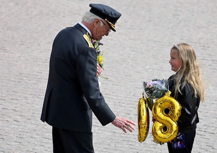 Dieses Mädchen hat an ihrem Strauß für den König aufblasbare Zahlen, die eine „80“ bilden, und ...