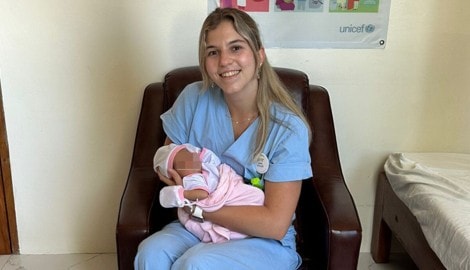 Laura Müller mit einem neugeborenen Baby während ihres Praktikums auf den Philippinen
