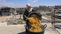 Eine Frau kocht auf dem Dach ihres Hauses in Gaza, um bedürftige Kinder mit einer Mahlzeit zu ...