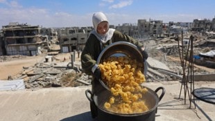 Eine Frau kocht auf dem Dach ihres Hauses in Gaza, um bedürftige Kinder mit einer Mahlzeit zu ...