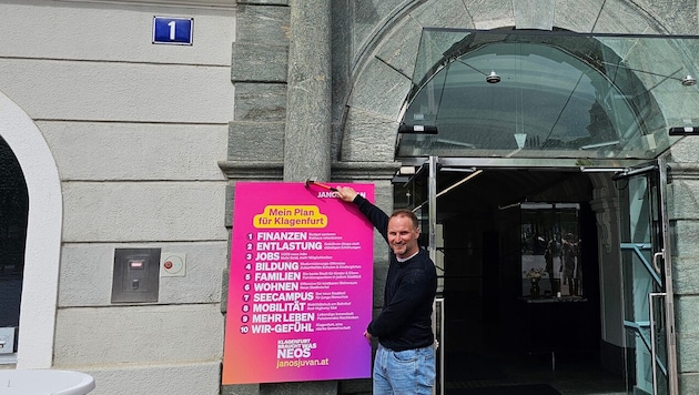 Janos Juvan heftet seine zehn Forderungen für die Stadt Klagenfurt fest an das Rathaustor.