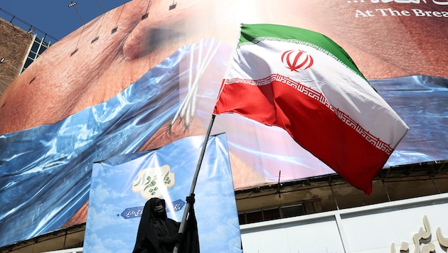 Eine Regime-Unterstützerin schwenkt die iranische Flagge in Teheran.