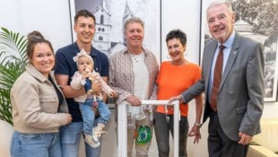 Bürgermeister Klaus Schneeberger (re.) übergab das Fenster samt buntem Fisch an Familie Tremmel.