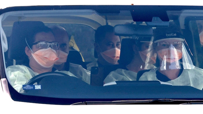 Ärzte in Schutzanzügen bei einem Transport von mehreren infizierten Personen in Australien