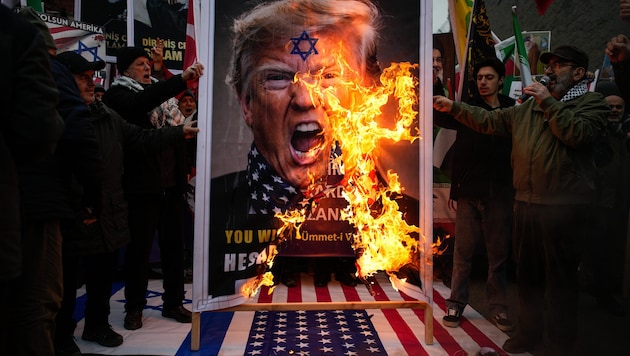 Demonstranten verbrennen ein Plakat von US-Präsident Donald Trump bei einer Kundgebung zur ...