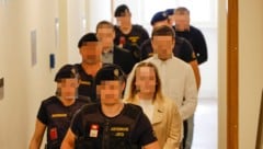 Die Angeklagten im Salzburger Landesgericht, bewacht von Justizwachebeamten.