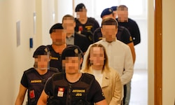 Die Angeklagten im Salzburger Landesgericht, bewacht von Justizwachebeamten.
