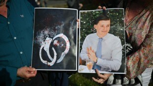 Menschen halten Bilder des Opfers Henry Nowak und blutverschmierte Handschellen in den Händen, ...
