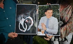Menschen halten Bilder des Opfers Henry Nowak und blutverschmierte Handschellen in den Händen, ...