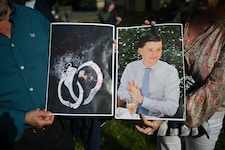 Menschen halten Bilder des Opfers Henry Nowak und blutverschmierte Handschellen in den Händen, ...