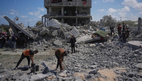 Palästinenser inspizieren die Trümmer eines Gebäudes, das bei einem israelischen Luftangriff in ...