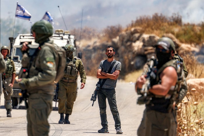 Ein bewaffneter Siedler zwischen den israelischen Soldaten