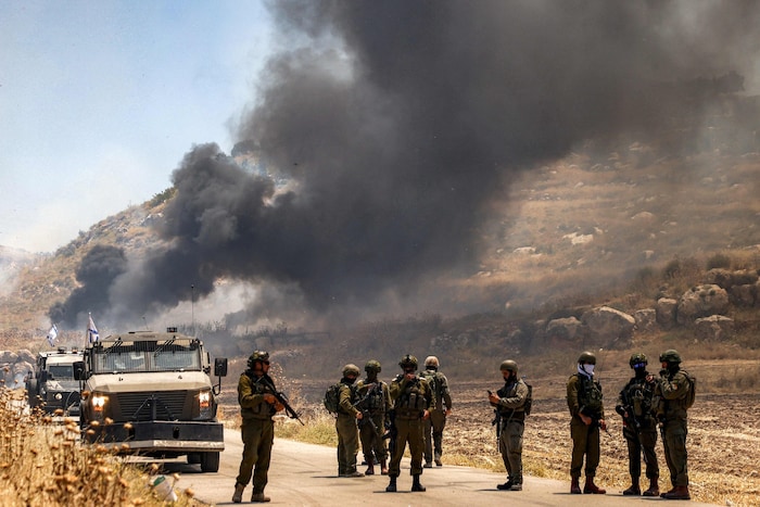 Israelische Soldaten vor einem Feld, dass Berichten zufolge von Siedlern in Brand gesteckt ...