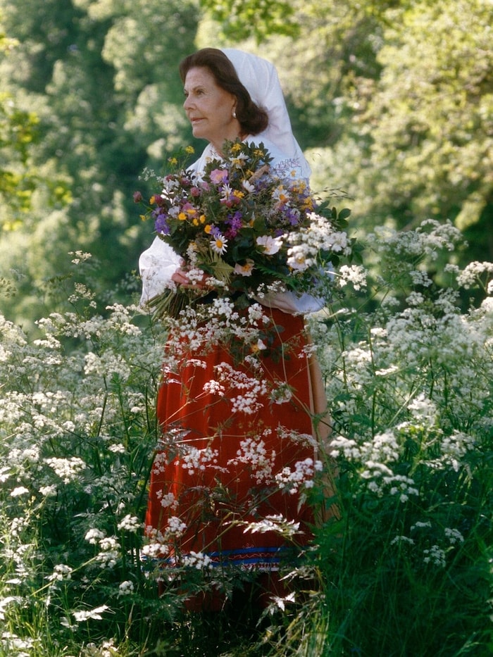 Die Königin mit einem Wiesenblumenstrauß, der wie selbst gepflückt wirkt.