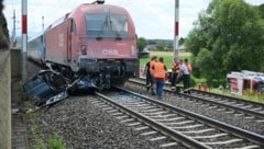 Das zerstörte Auto mit Zug und Einsatzkräfte auf den Bahngleisen