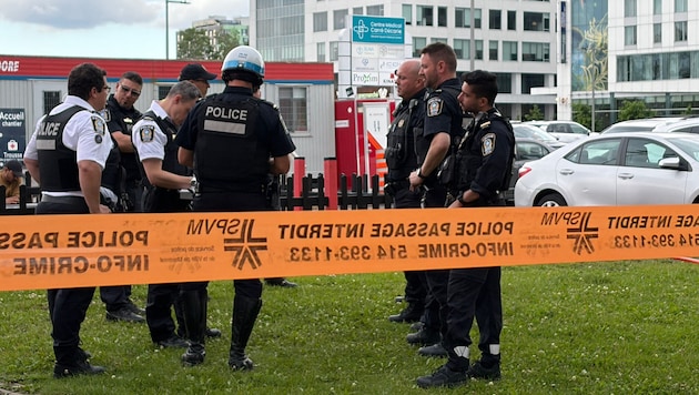 Die Polizei versammelte sich zu einer Besprechung in der Nähe des Tatorts. Zerbrochene Fenster ...