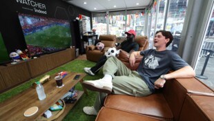 Austin Franklin und Kevin Akoto sitzen in einem Glaskasten auf dem Times Square in New York und ...