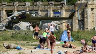 Menschen baden neben russischer Militärausstattung auf der Krim.