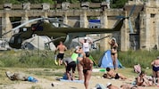 Menschen baden neben russischer Militärausstattung auf der Krim.