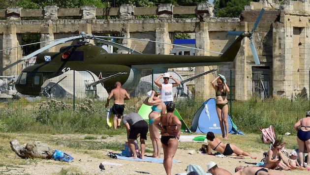 Menschen baden neben russischer Militärausstattung auf der Krim.