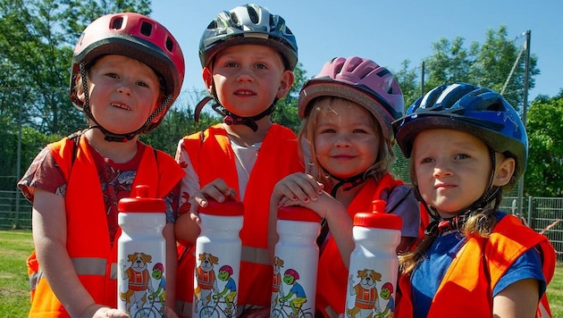 Kleine Radfahrer zeigen ihr Können und werden mit einer Trinkflasche belohnt.