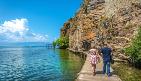 Am Ufer des Ohridsees schlängelt sich ein Holzweg durch eine Landschaft zwischen Bergen und ...