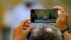 Ein Mann hält die öffentliche Auspeitschung des Paares filmisch mit seinem Smartphone fest.