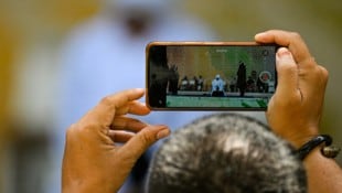 Ein Mann hält die öffentliche Auspeitschung des Paares filmisch mit seinem Smartphone fest.