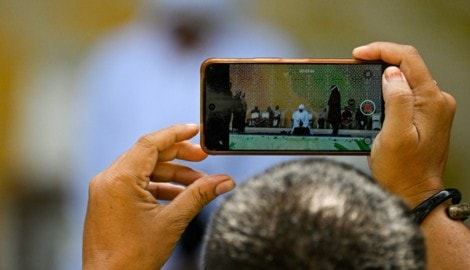 Ein Mann hält die öffentliche Auspeitschung des Paares filmisch mit seinem Smartphone fest.