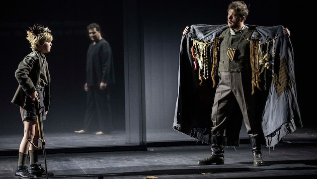 Tamino als Junge und Papageno (Sean Michael Plumb) mit Schwarzmarktware. Im Hintergrund (mi.) ...