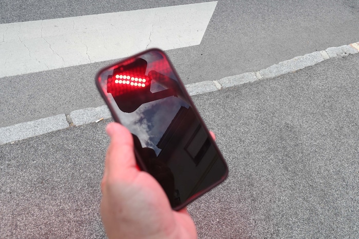 Das zusätzliche Rotlicht wird auf den Gehsteig projiziert und am Smartphone-Display reflektiert. ...