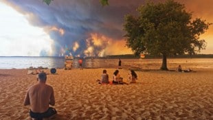 Urlauber am Strand von Lacanau (Frankreich) beobachten die Feuerwalze.
