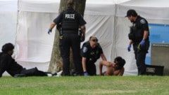 Polizisten kümmern sich nach der Schießerei um einen Mann.