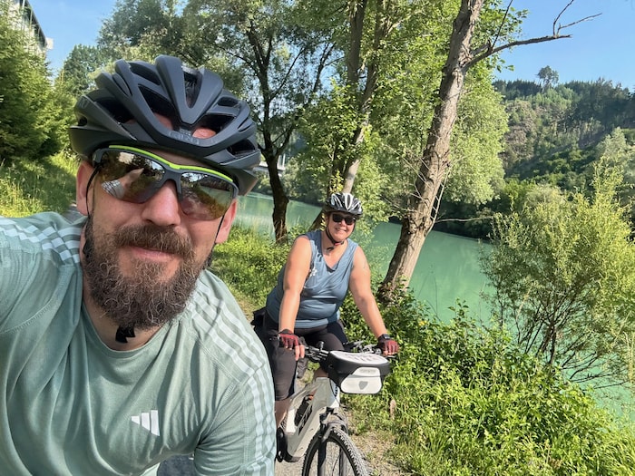 Wir radeln entlang von Flüssen und durch grüne Wiesen – Kühe und Bergpanorama inklusive.