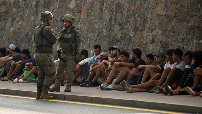 Spanische Soldaten bewachen festgenommene Migranten in Ceuta.