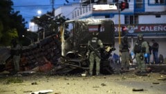Polizisten untersuchen nach der Explosion die Trümmer eines Lastwagens.
