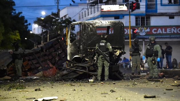 Polizisten untersuchen nach der Explosion die Trümmer eines Lastwagens.
