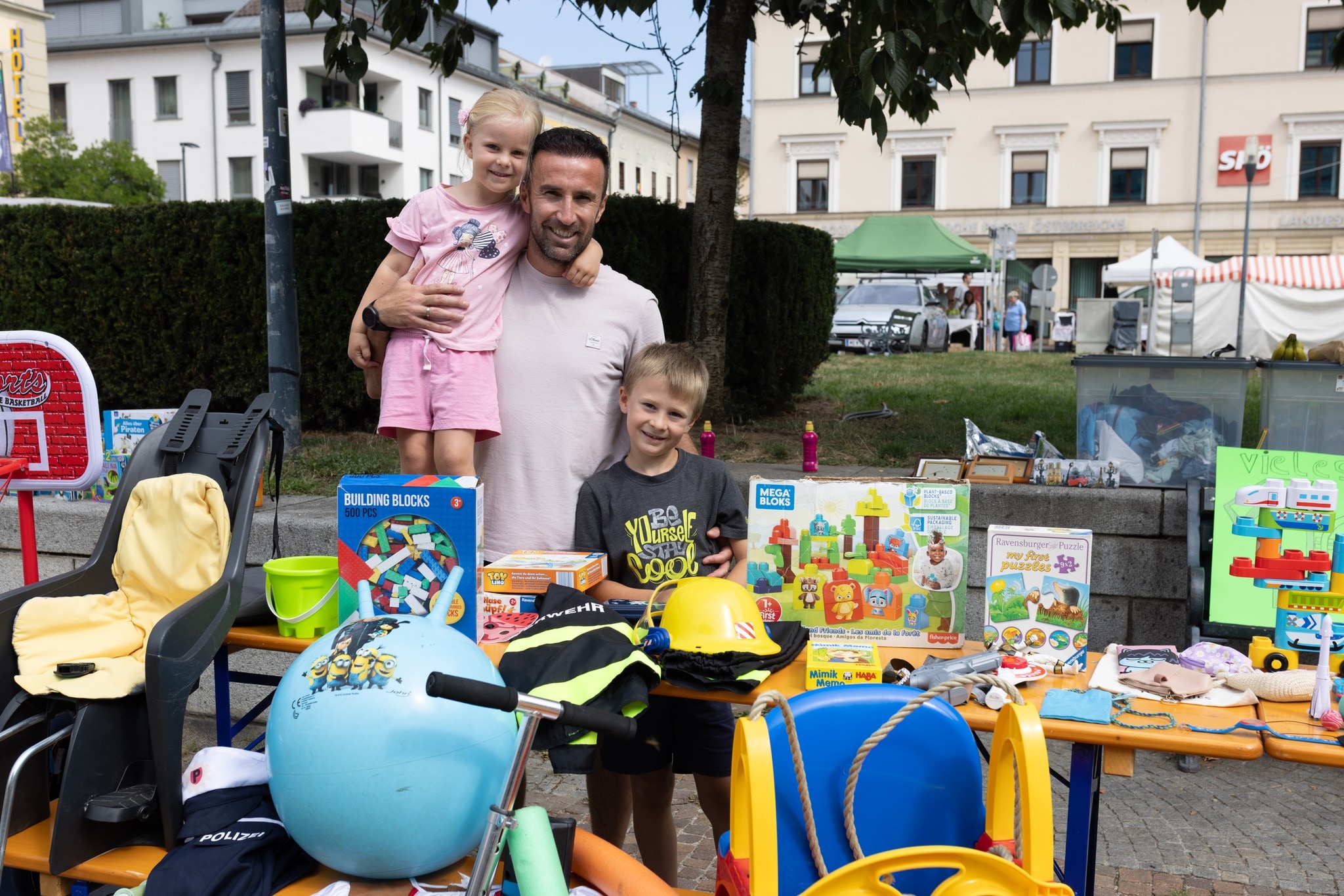 Alina und Samuel verkaufen mit Papa Erwin am Kinderflohmarkt Spielsachen.