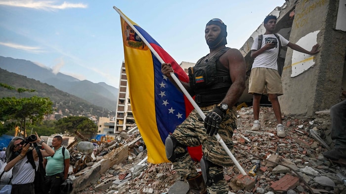 Ein Mann steht mit der venezolanischen Flagge auf den Trümmern eines eingestürzten Wohnblocks. ...