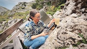 Mit einem Becher misst Maja die Schüttung der Wasserquelle.