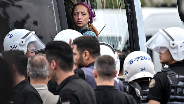 Eine der verhafteten Personen wird in einen Polizeibus eskortiert.